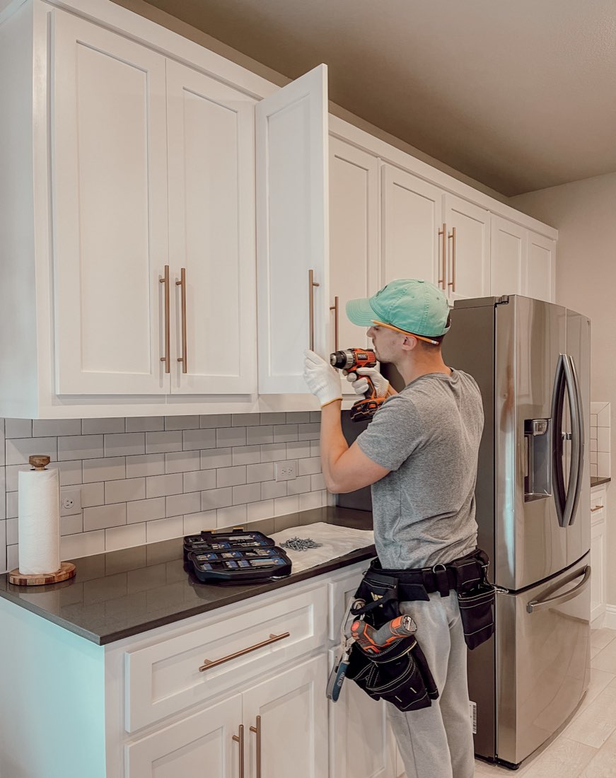 Installer drilling a cabinet door for new hardware