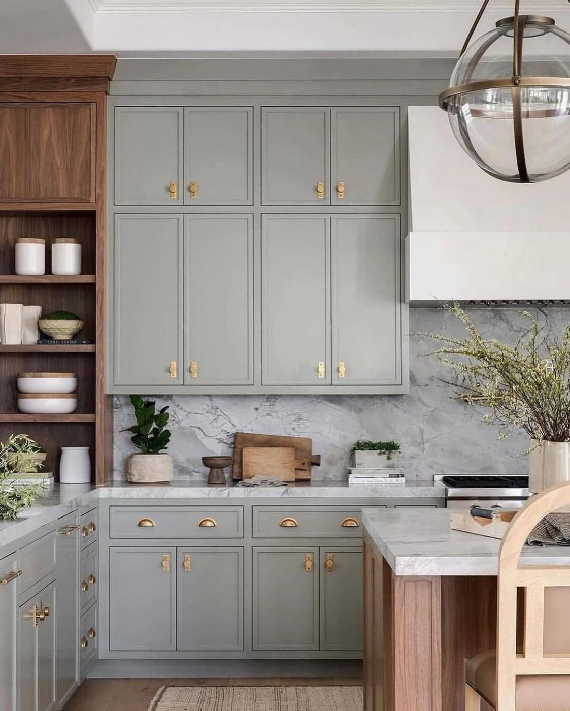Sage green kitchen cabinets fitted with brass cup pulls