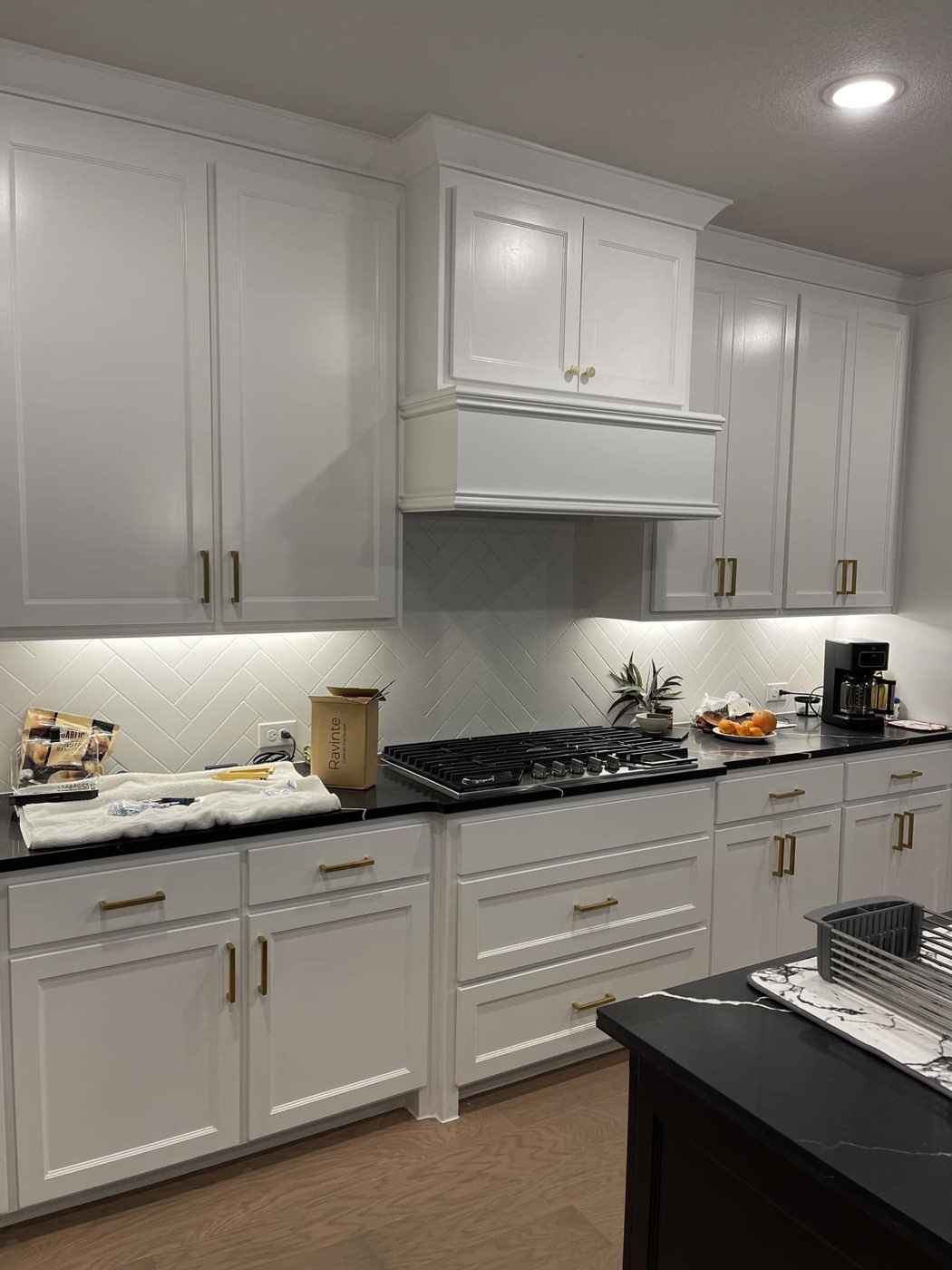 White kitchen mid-installation with new hardware box and brass pulls already in place