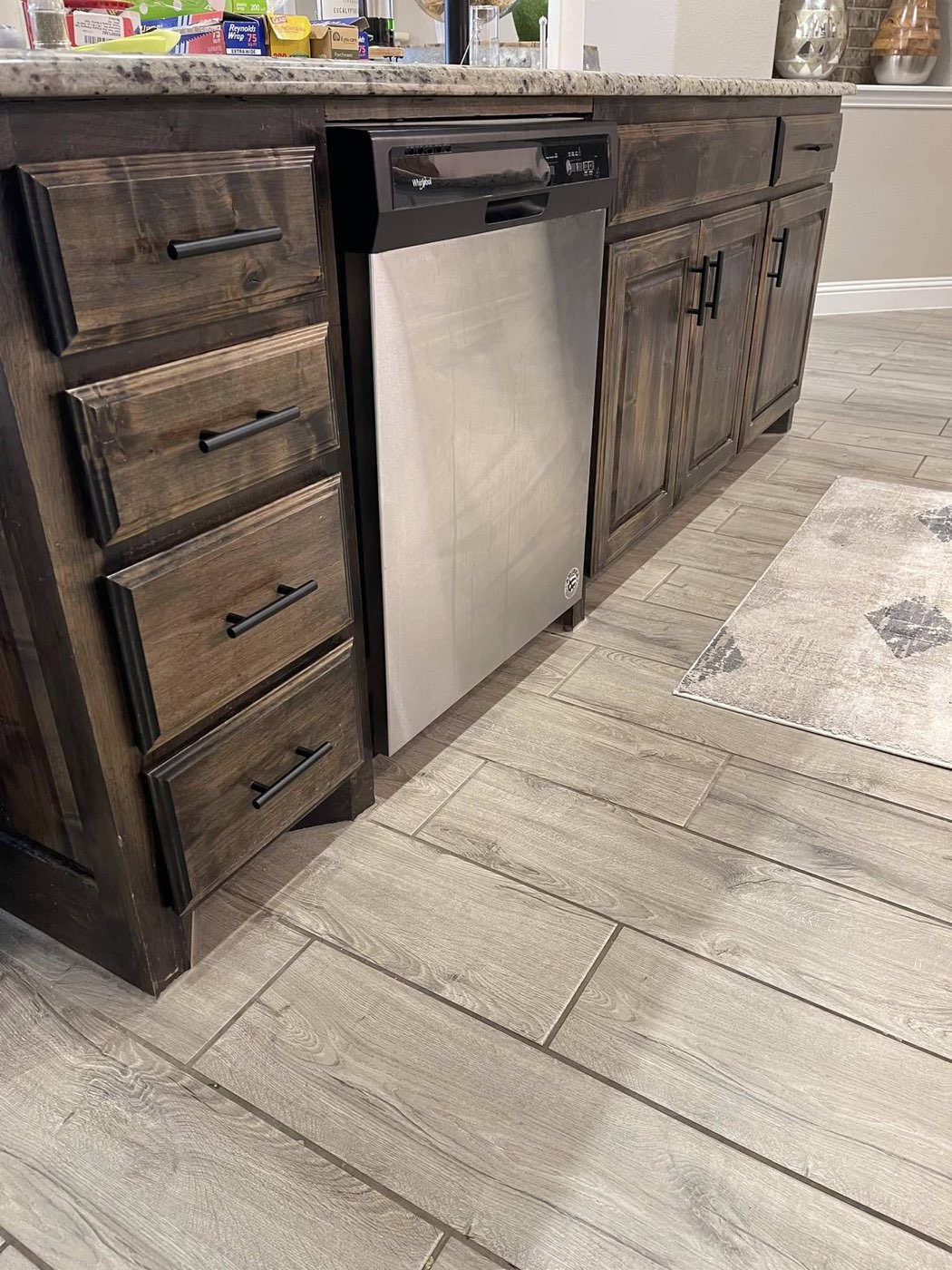 Dark stained kitchen island with built-in dishwasher and black bar pulls